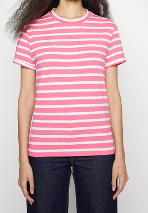 Rosa-weiß gestreiftes Baumwoll-T-Shirt mit kurzen Ärmeln und rundem Ausschnitt, entworfen in lockerer Passform. Kombiniert mit dunkelblauen Jeans.