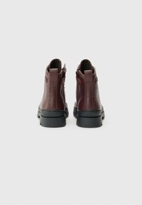 Bottines en cuir bordeaux à finition texturée, dotées de fermetures éclair à l'arrière, de semelles en caoutchouc et d'un design épuré.
