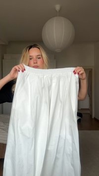 Jupe plissée blanche en tissu léger, dotée d'une taille élastique. La texture semble lisse et nette.