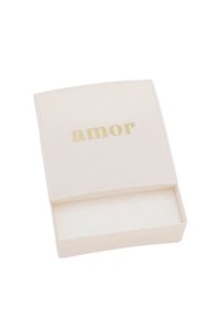 Krämfärgad låda med en slät matt yta. Ordet "amor" är pr präglat i guld på toppen. Inuti är den klädd med mjukt, vitt material.