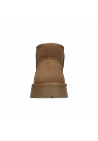 Bruine suède enkellaars met zachte voering, ronde neus en textuur rubberen zool. Voorzien van decoratieve stiksels langs de naden.