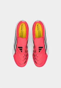 Φωτεινά ροζ αθλητικά παπούτσια με μαύρες διακοσμητικές ρίγες, διαθέτοντας υφή στο πάνω μέρος και ανοιχτό σχέδιο. Κίτρινη σόλα με εμφανή λογότυπο.