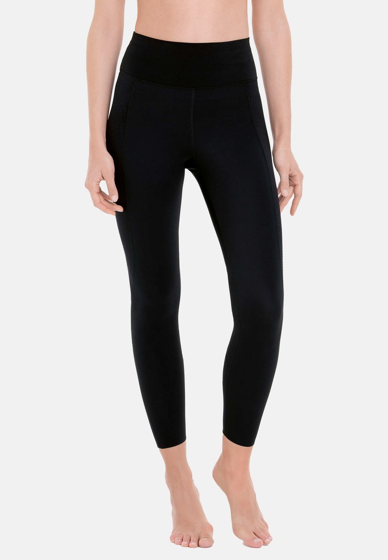Zwarte leggings met een hoge tailleband, gemaakt van rekbare stof, met zijnaad en een slim fit ontwerp dat naar de enkels toe tapsert.