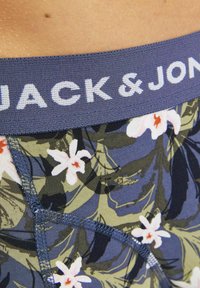 Boxer shorts en tissu doux avec une taille marine affichant "JACK & JONES". Présente un motif floral vert et blanc.