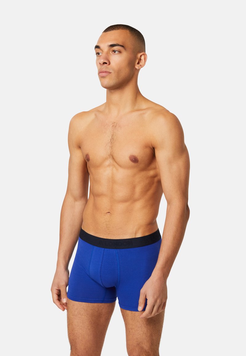 Blue cotton boxer shorts with a black elastic waistband, featuring a front pouch, fitted design, and visible stitching details.