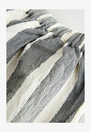 Tissu blanc avec des rayures noires texturées, froncé à la taille, présentant un matériau doux, respirant et une apparence froissée.