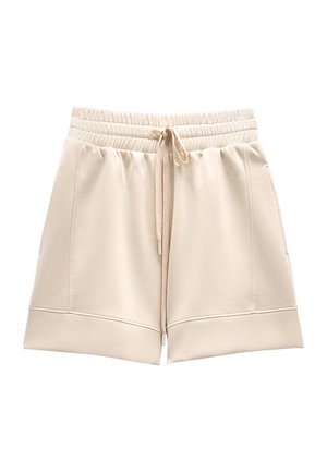 Beżowe szorty z elastycznym pasem, przednim sznurkiem i bocznymi kieszeniami, wykonane z miękkiego materiału z szerokimi podwiniętymi brzegami.