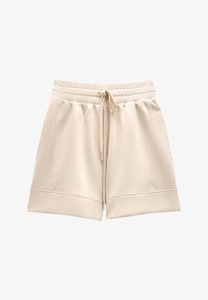 Beżowe szorty z elastycznym pasem, przednim sznurkiem i bocznymi kieszeniami, wykonane z miękkiego materiału z szerokimi podwiniętymi brzegami.