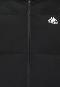 Czarna kurtka puchowa z zamkiem z przodu, z kontrastującą górną częścią w czerni. Zawiera białe logo Kappa na klatce piersiowej.