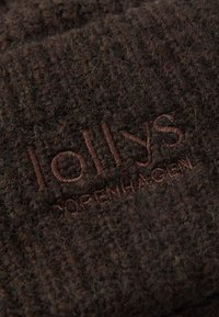 Hnedá vlnená zmesovina s textúrovaným povrchom, s vyšívaným logom "lollys copenhagen" v kontrastnej hnedej niťi.