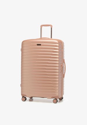 Tvrdý kufr v růžově zlaté barvě, s ribbovaným designem, zatahovací rukojetí a čtyřmi otočnými kolečky pro snadnou manipulaci.