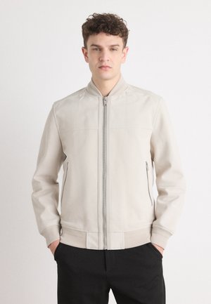 Giacca bomber beige chiaro con zip frontale, polsini e vita a coste, realizzata in tessuto morbido; presenta tasche laterali e colletto alla coreana.