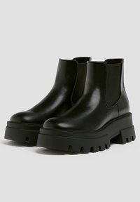 Bottes noires à la cheville en cuir lisse, dotées de panneaux latéraux élastiques, de semelles plateformes épaisses et d'une silhouette élégante.