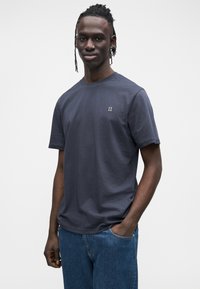 Granatowy bawełniany t-shirt z krótkimi rękawami i okrągłym dekoltem, z subtelnym haftowanym logo "II" na lewej piersi.