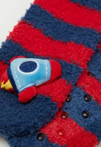 Rød og blå stribet fleece-stof med en blød raket-applikation. Har en blød tekstur og små sorte knapper indlejret i designet.