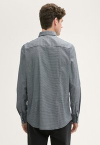 Graues, langärmliges Hemd mit Knopfleiste aus strukturiertem Stoff, geradem Rückenpasse und abgerundetem Saum. Verfügt über eine geknöpfte Manschette und ein dezentes Muster.