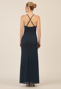 Abito da sera blu navy con spalline incrociate, busto aderente, gonna svasata e un leggero luccichio. Presenta una chiusura con zip sul retro per una facile vestibilità.