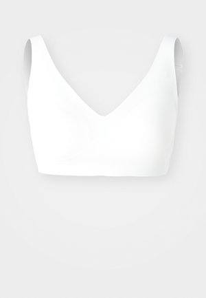 Bralette blanche sans couture avec un décolleté en V, des bretelles larges et une texture douce et lisse ; conçu pour le confort et une visibilité minimale sous les vêtements.