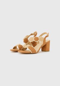 Ruskeat ja beige korkea korolliset sandaalit, joissa on pyöreät leikkuut, tiilijalkapohja ja säätövyö nilkassa. Pehmeä mokka ja sileä nahkamateriaali.