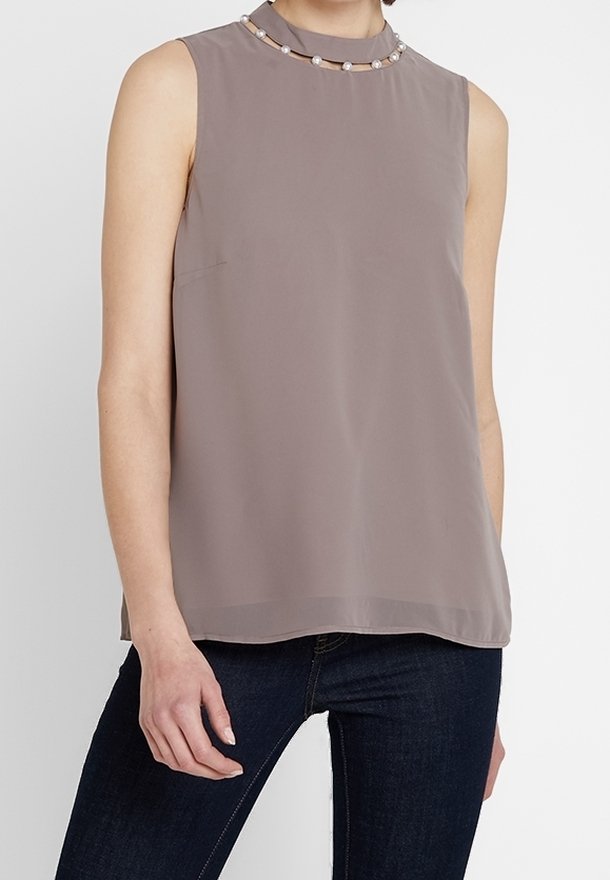 Haut sans manches en taupe clair avec un col haut. Présente un accent perlé au niveau du col et une texture de tissu lisse et fluide.