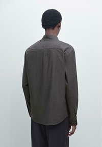 Donkergrijze overhemd met lange mouwen, een rug yoke-detail en een afgeronde zoom. Vlotte stofstructuur en klassiek kraagontwerp.