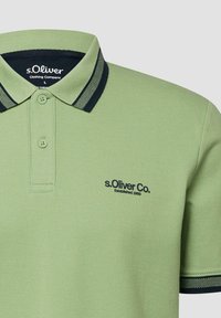 Polo vert clair avec col et poignets de manches à rayures vert foncé, arborant le logo "s.Oliver Co. Established 1969" sur la poitrine.