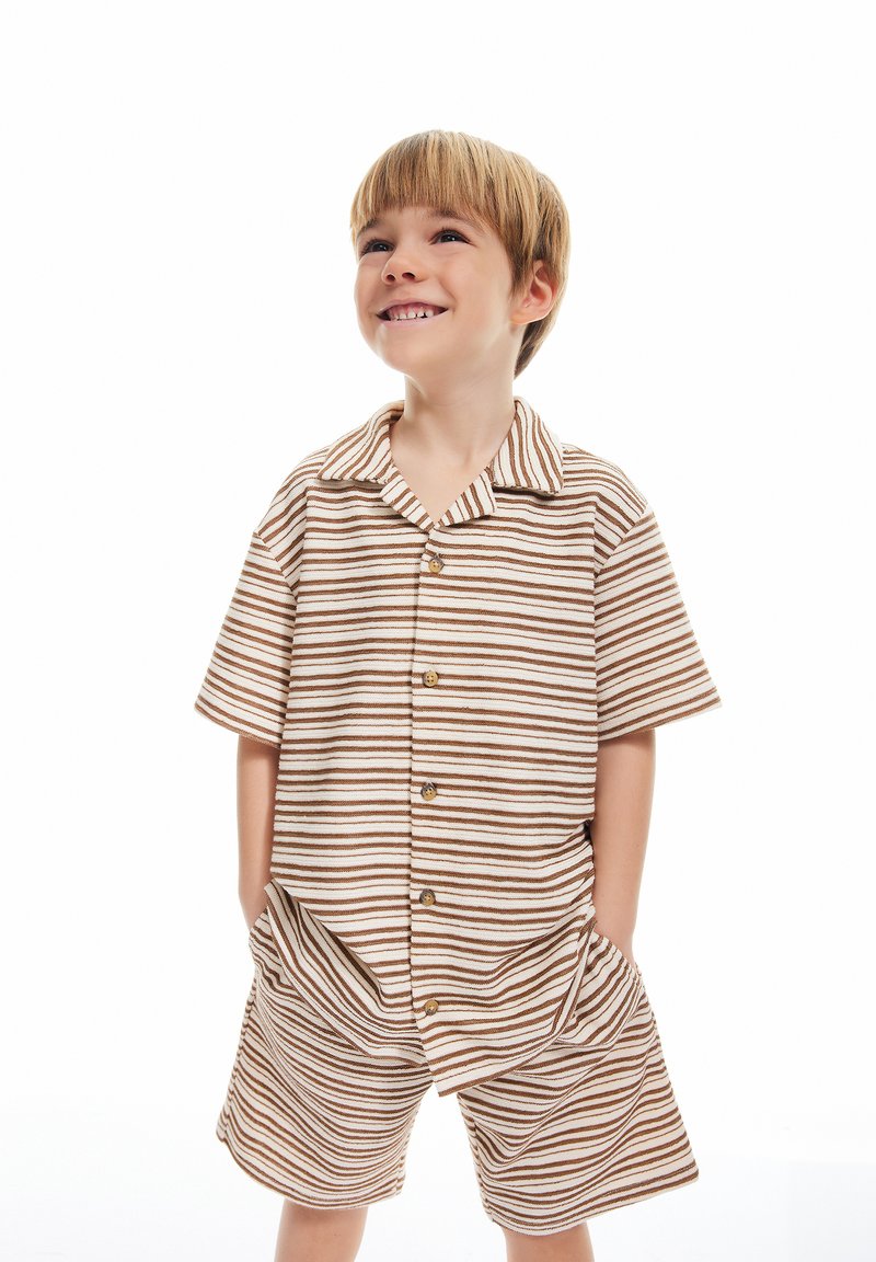 Randig kortärmad skjorta och shorts-set i beige och bruna nyanser, med knappar och sidofickor, tillverkat av mjukt tyg.