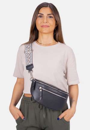 Schwarze Leder-Umhängetasche mit strukturierter Oberfläche, ausgestattet mit silbernen Reißverschlüssen und einem gemusterten Gurt. Das Design ist kompakt und praktisch.