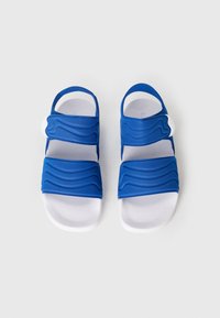 Μπλε σανδάλια με σχέδιο κυμάτων, δύο ρυθμιζόμενους ιμάντες και λευκή υφή στην επιφάνεια του πέλματος. Κλειστός βρόχος στη φτέρνα για ασφαλή εφαρμογή.