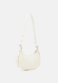 Bílá kožená kabelka přes rameno s zakřiveným tvarem, zipovým uzavřením a nastavitelným popruhem se stříbrnými prvky. Hladký povrch.