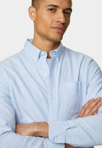 Lichtblauw button-up overhemd van zachte stof, met een zak op de linkerborst, knoopdetails en lange mouwen.