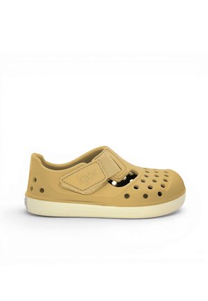 Hellbrauner Kinderschuh mit Belüftungslöchern, einem Klettverschluss und einer weißen Sohle, von der Seite auf weißem Hintergrund gezeigt.
