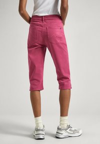 Rosa cropped byxor i bomullsmaterial, med fram- och bakfickor, synlig sömnad och raka ben.