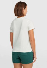 White cotton t-shirt with short sleeves, round neckline, and a straight cut, paired with dark green denim shorts featuring back pockets.
