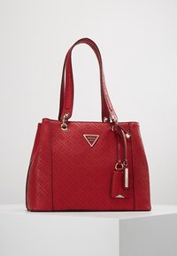 Rode synthetische handtas met een geprofileerd patroon, dubbele handgrepen, zilverkleurige hardware en een logo-plaatje. Inclusief een afneembare tag.