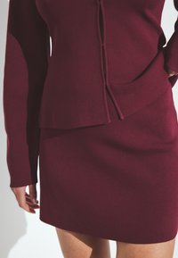 Burgundy stickad klänning med långa ärmar, med en lagerdesign, texturerad tyg och en åtsittande silhuett. Inga synliga mönster eller hårdvara.