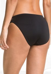 Bottom da bagno nero con un design a taglio alto, texture morbida e cuciture a contrasto. Presenta una copertura minima e si posiziona appena sopra i fianchi.