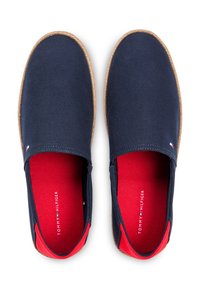 Μπλε καμβά παπούτσια χωρίς κορδόνια με κόκκινα εσωτερικά πέλματα, διακόσμηση από ψάθα και λογότυπο. Στρογγυλή μύτη και επίπεδη σόλα σχεδιασμένα για καθημερινή χρήση.