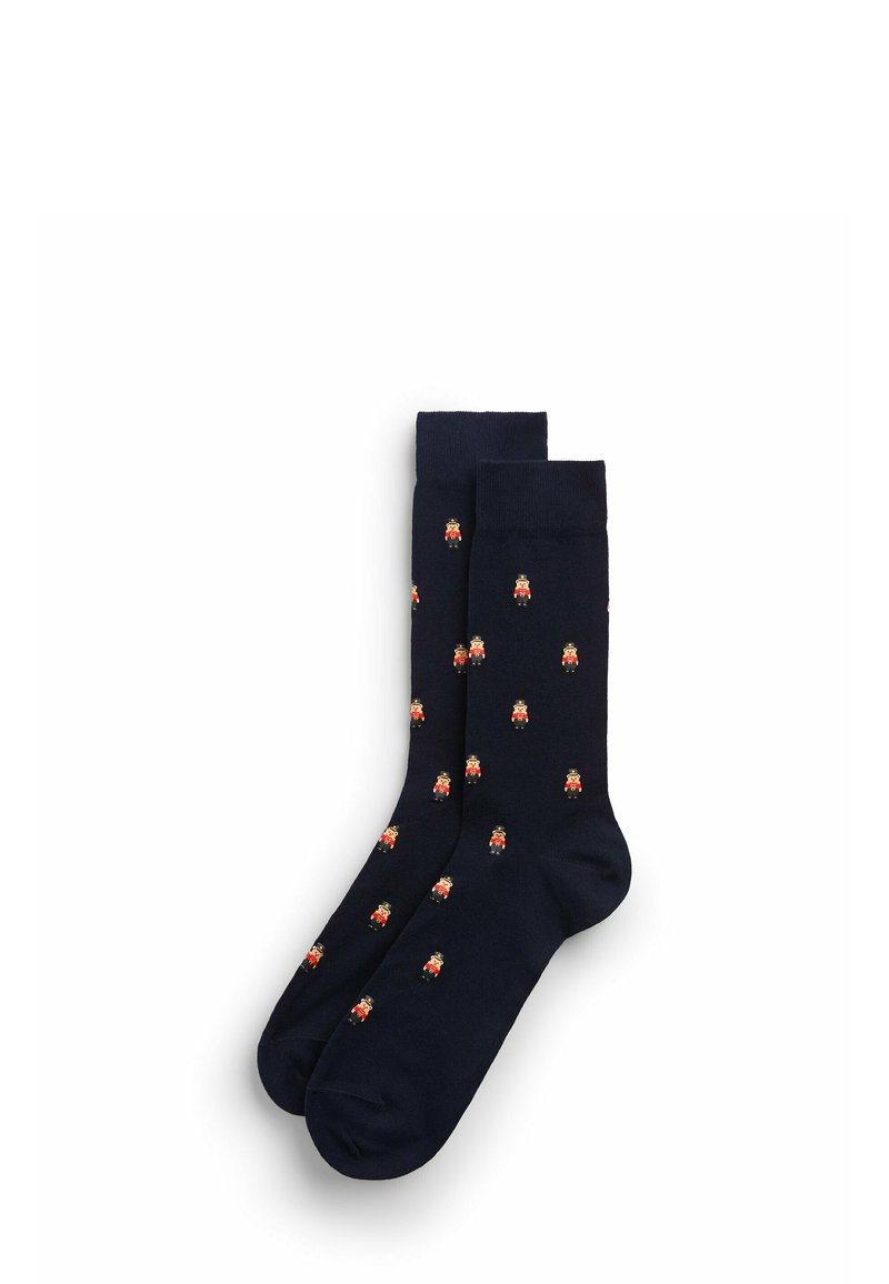 Un par de calcetines azul marino con un patrón repetido de pequeños soldados de cascanueces en tonos rojos, negros y beiges.