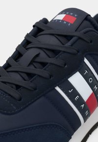 Sneaker blu navy realizzati in suede e rete, con un design testurizzato, lacci piatti e dettagli del logo rosso, bianco e blu.