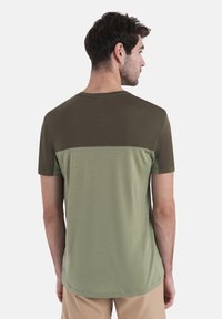 T-shirt a maniche corte con un design a blocchi di colore in olivo scuro e olivo chiaro, realizzato in un tessuto morbido e liscio con scollo tondo.