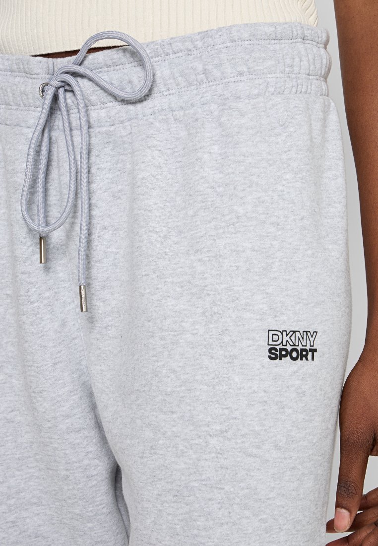 Szare dresowe spodnie DKNY Sport z elastycznym paskiem w talii, sznurkiem do regulacji i bocznymi kieszeniami. Charakteryzują się czarnym logo na nodze. Wykonane z miękkiego materiału bawełnianego.