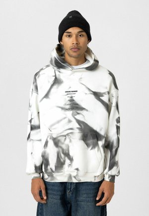 Witte en zwarte tie-dye hoodie met kangoeroezak, verstelbare trekkoordcapuchon en bedrukte tekst op de voorkant. Zware stof.