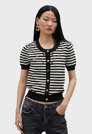 Black-and-white striped cardigan with short puff sleeves, embellished with colorful gems, featuring a round neckline and gold buttons.