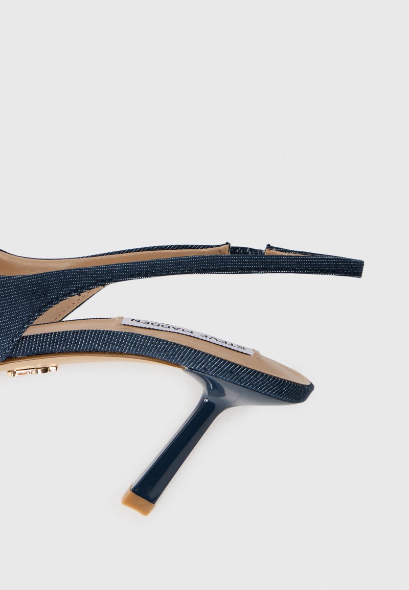 Sandales à talons bleu marine avec une tige en tissu texturé, des brides étroites et un embout pointu. Elles présentent un fin talon aiguille et une semelle intérieure beige.