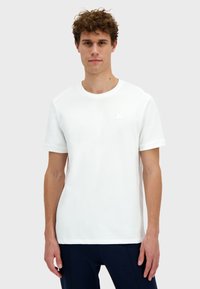 Bílé bavlněné tričko s krátkým rukávem, kulatým výstřihem a malým, embosovaným logo na hrudi. Hladká textura a klasický střih.