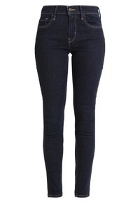Jeans skinny de mezclilla de lavado oscuro con cintura alta, que cuentan con cierre de botón, cinco bolsillos y detalles de costura en contraste.