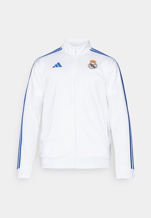 Bela športna jakna z modrimi progi, visok ovratnik, poln zadrgo in logotip Real Madrid na levi prsni strani. Narejena iz lahkega materiala.