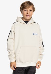 Felpa leggera beige con tasca frontale, cappuccio con coulisse e dettagli neri sulle spalle. Presenta un logo blu e bianco sul petto.