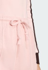 Ružové froté tepláky s elastickým pásom. Obsahujú mäkkú štruktúru, bočné vrecká a voľný strih pre pohodlie.